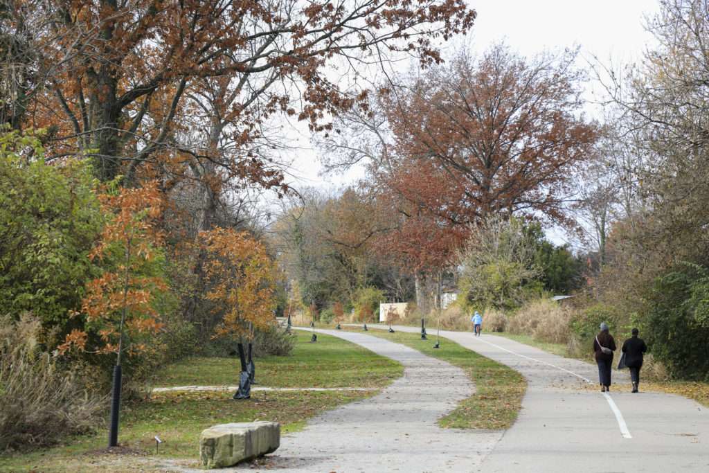 people walking and cycling on the Wasson Way trail in fall weather.
