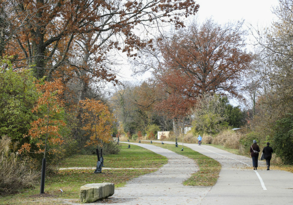 people walking and cycling on the Wasson Way trail in fall weather.